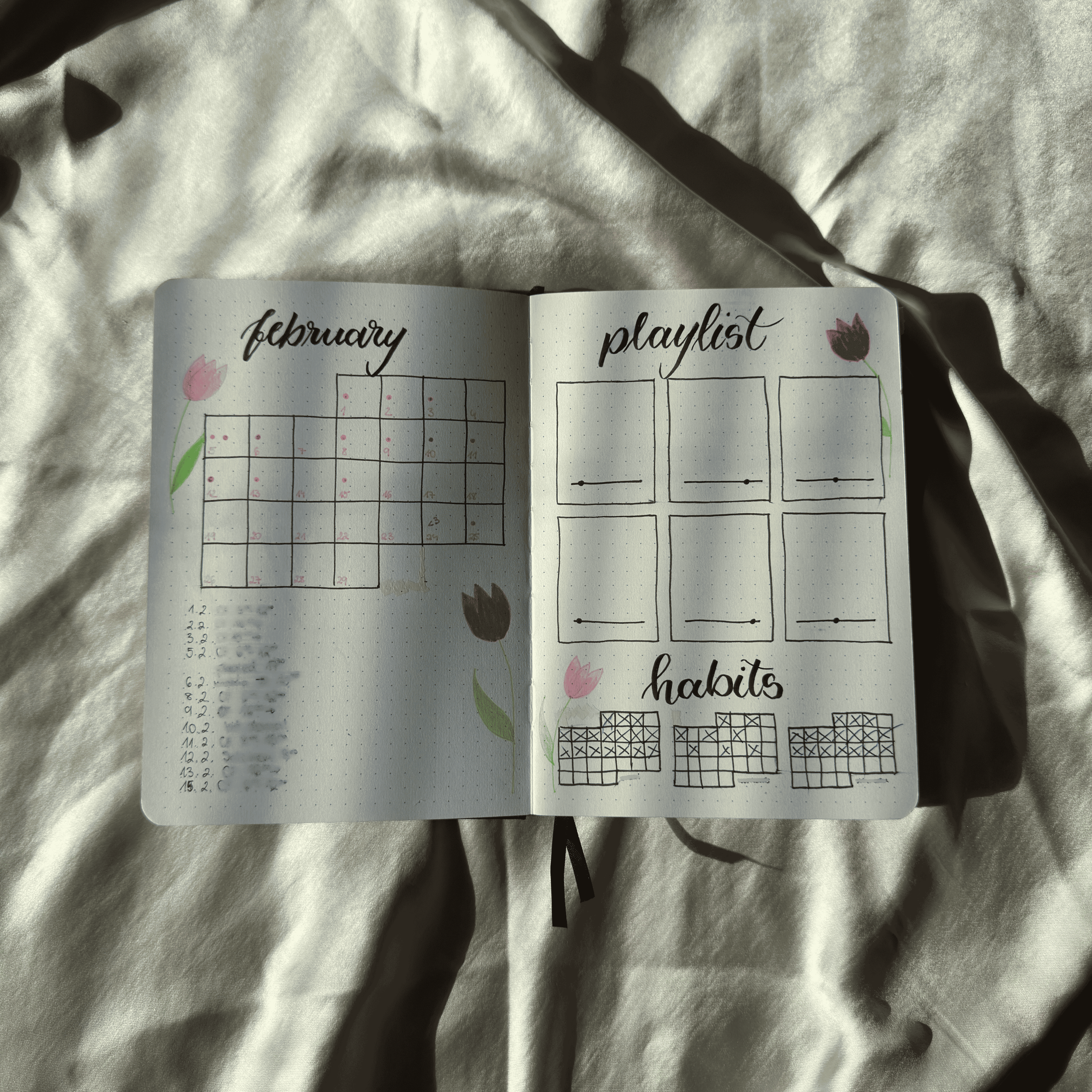 Open notebook with February calendar and playlist on a textured surface